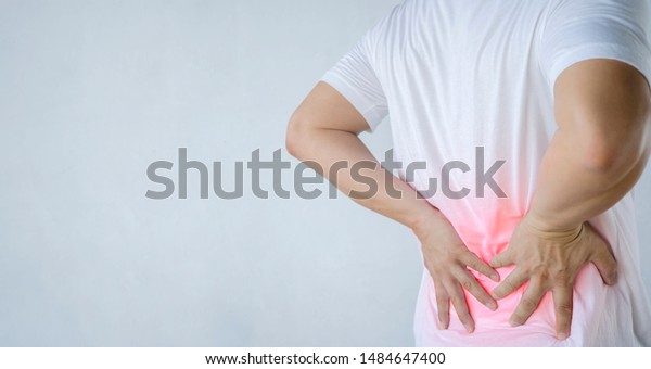 Back pain concept, kidney inflammation, man\
suffering from backache at home, red inflamed zone, panorama.\
Wearing a white shirt, gray\
background