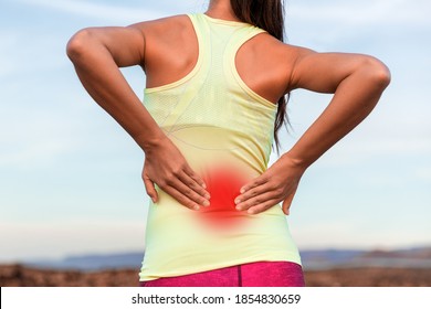 Rückenschmerzen Sportverletzung Frau mit entzündetem Bereich in rotem Hals. Junge Sportler berührende Massage Wirbelsäulenmuskeln roden unteren Rücken, beschnitten Torso von hinten.