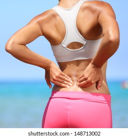 Back Pain - Woman Having Painful Muscle Injury In Lower Back. Fitness Girl Sport Girl With Sports Injury Outdoor On Beach.