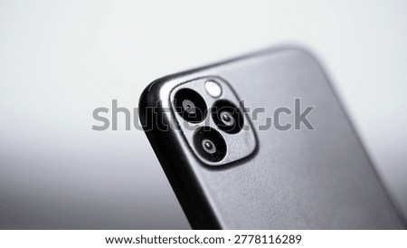 The back panel of a mobile phone with three camera lenses, shooting close up