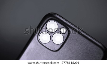 The back panel of a mobile phone with three camera lenses, shooting close up