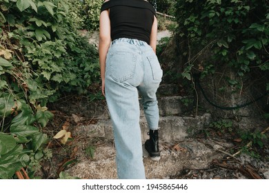 Back Part Of A Woman Wearing Mom Jeans Surrounded By Plants And Modern Style