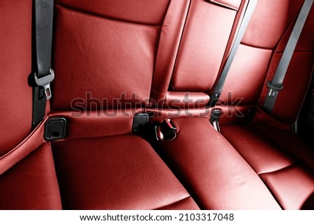 Back passenger red seats in modern luxury car. Red perforated leather with white stitching. Car detailing. Leather comfortable seats. Car interior details