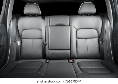Back passenger seats in modern luxury car, frontal view, black perforated leather