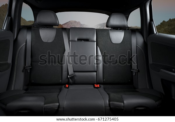 Back passenger seats in modern luxury car,\
black upholstery, mountains in the\
windows