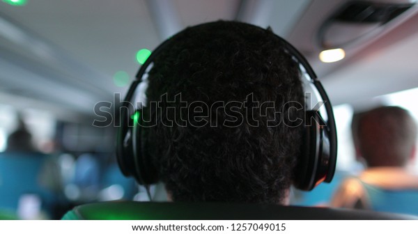 The back of a Person listening to music with\
headphones while traveling by\
bus