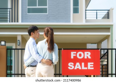 Back Portrait Of Asian Young Couple Standing And Hugging Together Looking Happy In Front Of Their New House To Start New Life. Family, Age, Home, Real Estate And People Concept.
