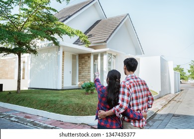 Back Portrait Of Young Couple Standing In Front Of Their New House