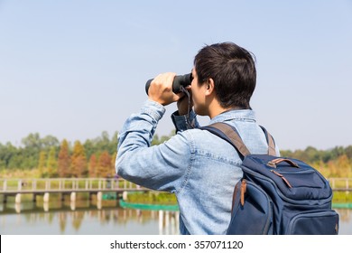 The Back Rear Of Man Using Binoculars For Birdwatching