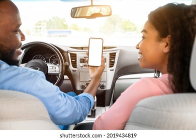 Back Rear Over The Shoulder View Of Happy Black Male Driver Holding Smartphone With Blank Screen, Mock Up. Closeup Of Mobile Phone With Empty Display, Couple Using Mobile App For Navigation, Copyspace