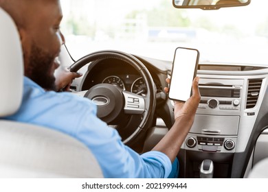 Back Rear Over The Shoulder View Of Happy Black Male Driver Holding Smartphone With White Blank Screen, Mock Up. Closeup Of Cellphone With Empty Display, Guy Using Mobile App For Navigation, Copyspace