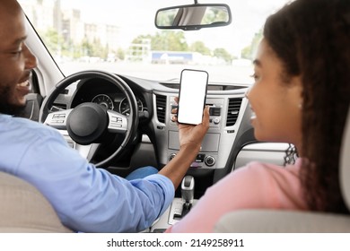 Back Rear Over The Shoulder View Of Happy Black Male Driver Holding Cell In Hand Showing White Blank Mock Up Screen To Female Passenger Sitting On Front Seat Using Mobile App For City Navigation