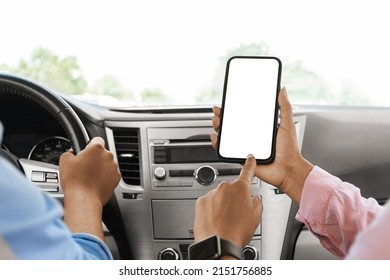 Back rear over the shoulder view of black female passenger holding cell phone pointing finger at white blank screen for mock up, sitting on front seat in car. Couple using app for navigation, closeup