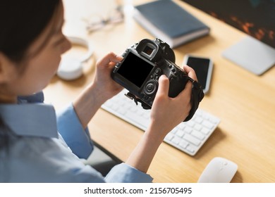 Back Rear Over The Shoulder View Of Female Photographer Woman Holding Camera Working With Photos Looking Through Taken Pictures At Home, Blank Empty Screen Mockup. Art And Creative Profession Concept