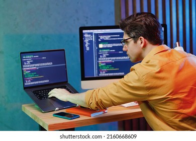 Back Rear Side Profile View Young Data Scientist Software Engineer IT Specialist Programmer Man Wearing Shirt Work At Home Writing Typing Code Script On Laptop Pc Computer. Game Development Concept