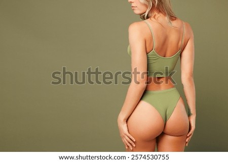 Back rear view close up cropped young lady woman with slim skinny body perfect skin she wear top bra lingerie stand put hand on buttocks isolated on plain green background. Lifestyle diet fit concept