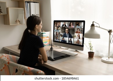 Vista posterior feliz empleada del milenio mirando el monitor de computadora, llevando a cabo negociaciones de videollamadas en línea con diversos colegas y gerente ejecutivo masculino, trabajando desde casa.
