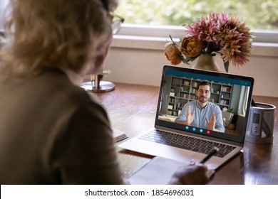 Back Rear View Middle Aged Older Woman Holding Online Conversation With Grown Up Son Or Enjoying Distant Educational Class With Young Male Tutor Using Video Call Computer Application At Home.