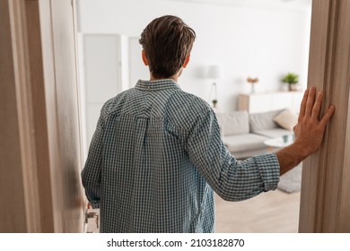 Back rear view of unrecognizable young man walking in his apartment, entering new home, casual guy standing in doorway of modern flat, looking at design interior, coming inside, selective focus