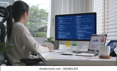 Back Rear View Of Young Asian Woman, Freelance Data Scientist Work Remotely At Home Coding Programing On Big Data Mining, AI Data Engineering, IT Technician Works On Artificial Intelligence Project.