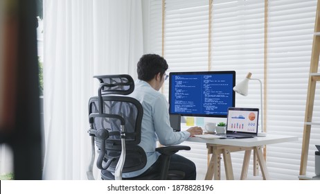 Back Rear View Of Young Asian Man, Freelance Data Scientist Work Remotely At Home Coding Programing On Big Data Mining, AI Data Engineering, IT Technician Works On Artificial Intelligence Project.