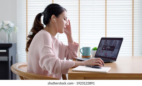 Back rear view young asian woman employee work from home using computer notebook videocall meeting conference angry annoy with low poor unreliable internet wifi connection problem issue outage.