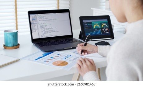 Back rear view of young asian woman, freelance data scientist work remotely at home coding programmer on Big data mining, AI data engineering, IT Technician Works on Artificial Intelligence Project.