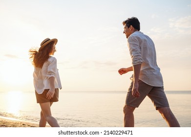 Back rear view young fun couple two friends family man woman in white shirt clothes hold hands walk run stroll together at sunrise over sea beach ocean outdoor exotic seaside in summer day evening.