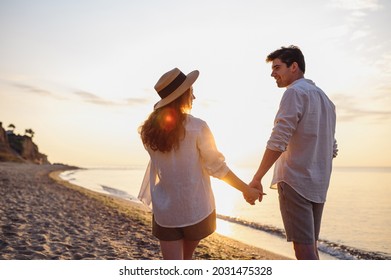 Back rear view young happy lovely couple two friends family man woman in summer clothes hold hands walking stroll together at sunrise over sea beach ocean outdoor exotic seaside in summer day evening - Shutterstock ID 2031475328