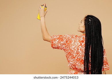 Back rear view young Latin woman she wearing orange casual clothes hold in hand paint spray bottle making graffiti isolated on plain pastel light beige background studio portrait. Lifestyle concept - Powered by Shutterstock