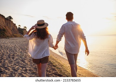 Back rear view young lovely couple two friends family man woman 20s in white shirt clothes hold hands walk stroll together at sunrise over sea beach ocean outdoor exotic seaside in summer day evening - Powered by Shutterstock