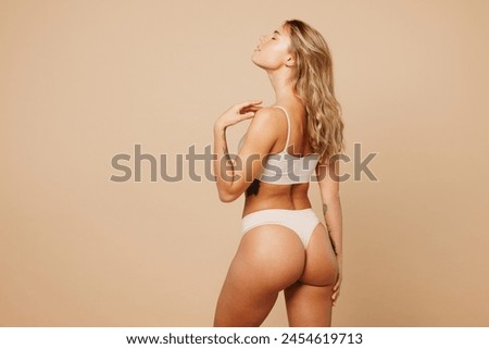 Back rear view young nice lady woman with slim body perfect skin wear nude top bra lingerie stand close eyes touch herself isolated on plain pastel light beige background. Lifestyle diet fit concept