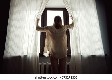 Back red haired young woman opening curtains in a bedroom - Powered by Shutterstock