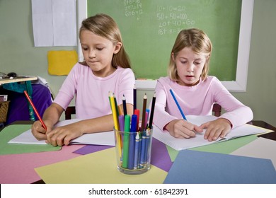 Back To School - 8 Year Old School Girls In Classroom Writing In Notebook