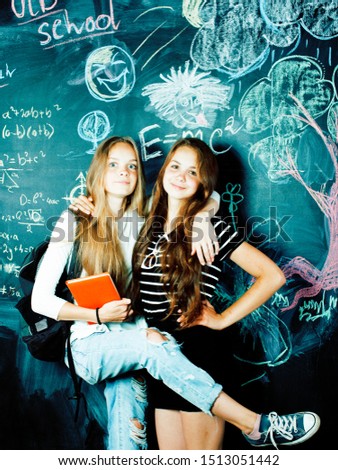 back to school after summer vacations, two teen girls in classroom with blackboard painted together