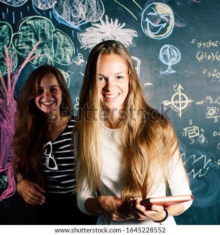 back to school after summer vacations, two teen girls in classroom with blackboard painted together