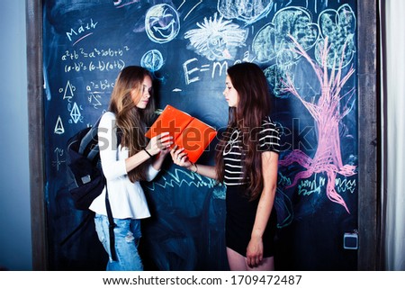 back to school after summer vacations, two teen real girls in classroom with blackboard painted together, lifestyle people concept