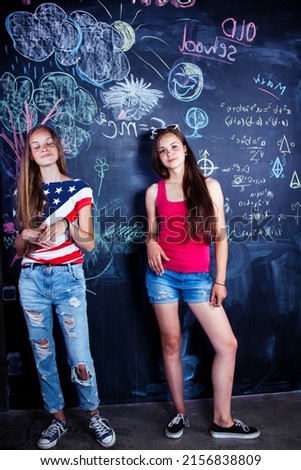 back to school after summer vacations, two teen girls in classroom with blackboard painted