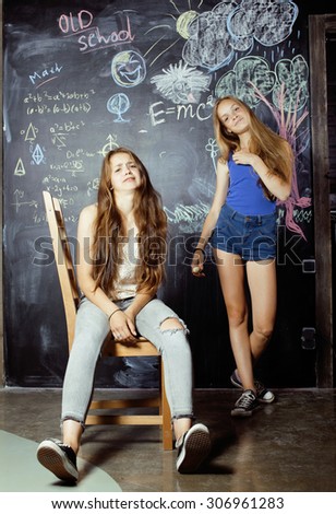 back to school after summer vacations, two teen real girls in classroom with blackboard painted together