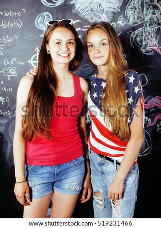 back to school after summer vacations, two teen real girls in classroom with blackboard painted together