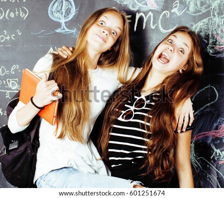 back to school after summer vacations, two teen real girls in classroom with blackboard painted together, lifestyle people concept close up