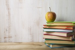 Back to school. Apple on a pile of books on a light wooden table., a School & Education Photo by Elena Blokhina