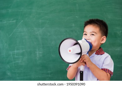 Back To School. Asian Funny Cute Little Child Boy Kindergarten Preschool In Student Uniform Speaking Through Megaphone Against On Green School Blackboard, First Time To School Education Concept