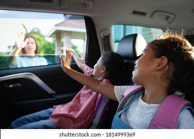 Back to school. Asian pupil girl with backpack and her sister sitting in the car and waving goodbye to her mother to get ready to school.