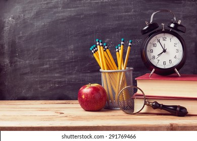 Back To School Background With Books And Alarm Clock Over Chalkboard