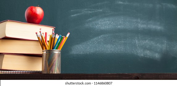 Back to school background with books and apple over blackboard