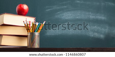 Back to school background with books and apple over blackboard