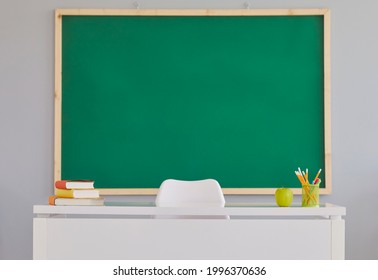 Back To School background with a clean green school board. Indoor shot of a teacher's desk and a copy space blackboard in a modern school classroom. Education concept - Powered by Shutterstock