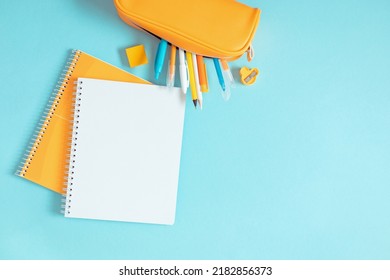 Back to school background. Flat lay, top view of colorful scattered stationery on isolated pastel blue table background. School supplies on desk. Copyspace.