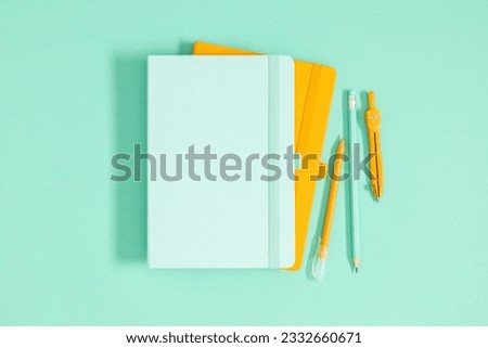 Back to school background. Flat lay, top view of school accessories, notebook, pens on isolated light green table background. School stationery on desk. Copyspace